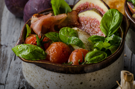 Herby salad, fresh figs, baked tomatoes, basil in and fresh roasted garlic toastsの写真素材