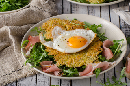 Potato pancakes with eggs and ham, fresh arugula saladの写真素材