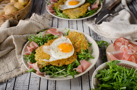 Potato pancakes with eggs and ham, fresh arugula saladの写真素材