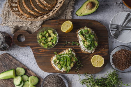 Delish fresh cheese on crisp bread, fresh cheese with avocado and cucumber and healthy seeds on topの写真素材