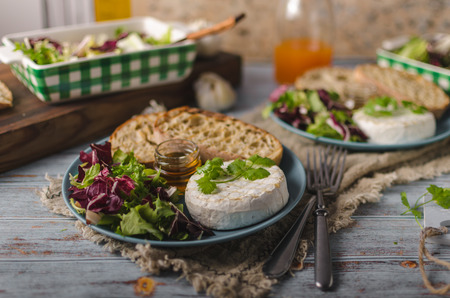 Delicious cheese, fresh salad and herbs with honeyの写真素材