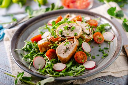 Delicious chicken roulade filled with herbs and ham, fresh salad with radishesの写真素材
