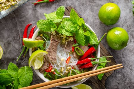 Traditional Vietnamese soup with chilli, noodles, fresh herbs and beef meat