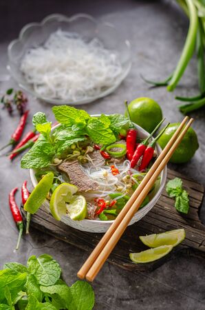 Traditional Vietnamese soup with chilli, noodles, fresh herbs and beef meatの写真素材