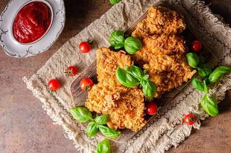 Delicous chicken steak in spicy cornflakes butter, bio herbs and ketchupの写真素材