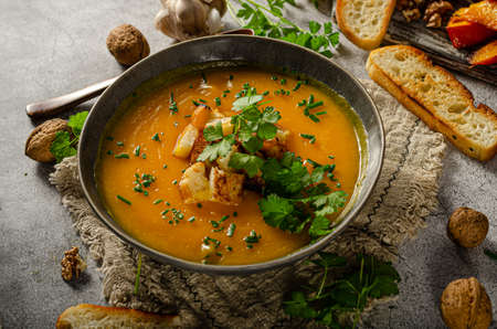 Creamy and delicious soup from roasted pumpkin, fresh herbs and crispy toastの写真素材