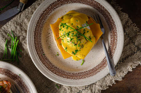 Organcic eggs benedict with bacon, cheddar cheese and herbs and hollandaise sauce