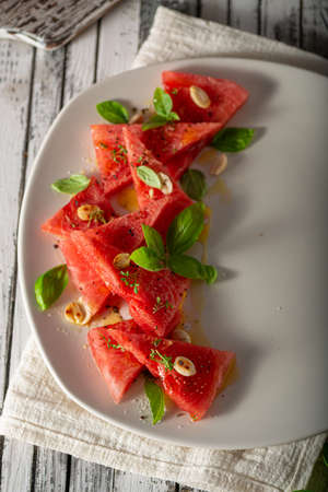Bio watermelon with nuts, basil and olive oilの写真素材