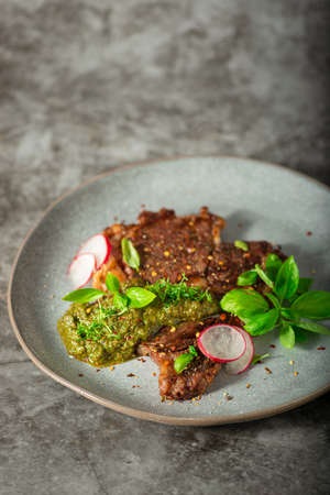 Delicious rib eye steak with pesto and garnishの写真素材