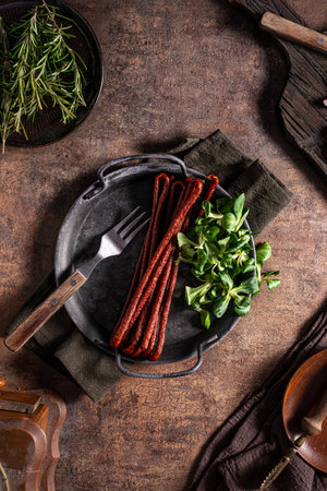 Smoked sausage with herbs on a rustic background. Top view.の写真素材