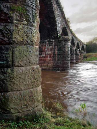 Swollenriver flowing under a bridgeの写真素材