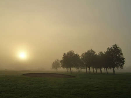 Sunrise through dense fog on a golf courseの写真素材
