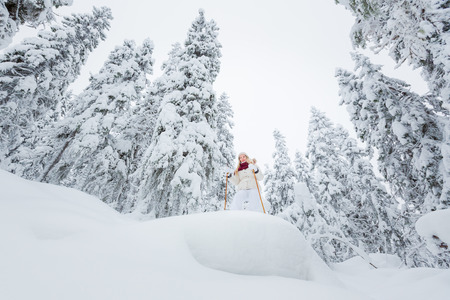 Young woman snowshoeing in snowy forest in winter