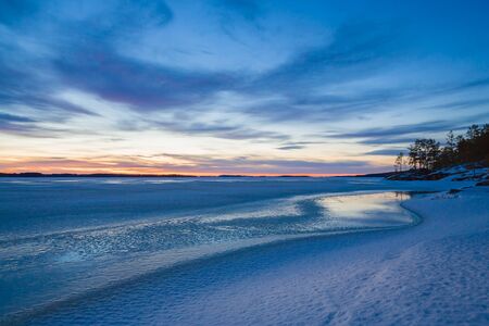 Cold winter landscape at sunset by the lakesideの写真素材