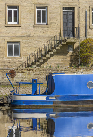 Blue painted narrowboat moored close to a sandstone buildingの写真素材
