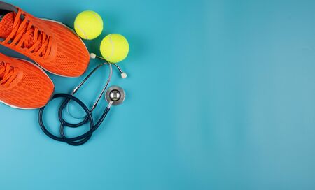 Orange sports shoes and stethoscope on the blue background. Concept exercise for good health.の写真素材