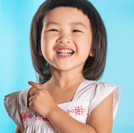 Cute asian girls show happiness. In various postures on a blue background with copy space.の写真素材