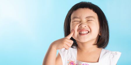 Cute asian girls show happiness. In various postures on a blue background with copy space.の写真素材