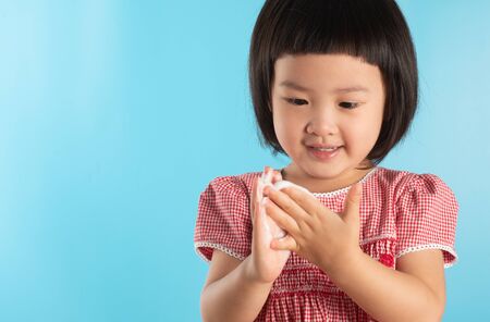 Cute Asian girl washing hands with soap bubbles to kill bacteria COVID - 19 for good health with fun and happiness. With copy space.の写真素材