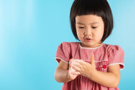 Cute Asian girl washing hands with soap bubbles to kill bacteria COVID - 19 for good health with fun and happiness. With copy space.の写真素材