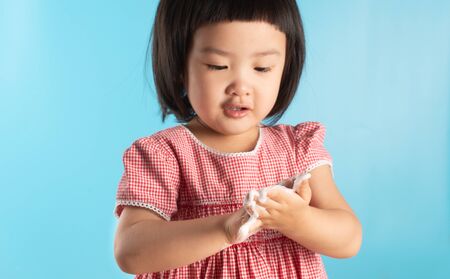 Cute Asian girl washing hands with soap bubbles to kill bacteria COVID - 19 for good health with fun and happiness. With copy space.の写真素材