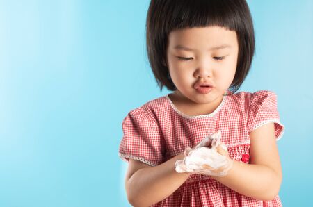 Cute Asian girl washing hands with soap bubbles to kill bacteria COVID - 19 for good health with fun and happiness. With copy space.の写真素材
