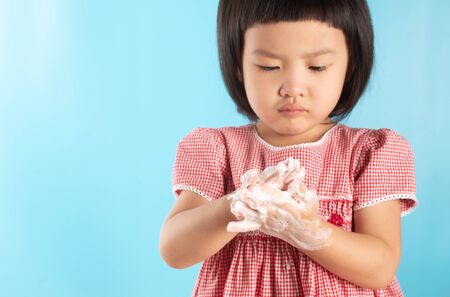 Cute Asian girl washing hands with soap bubbles to kill bacteria COVID - 19 for good health with fun and happiness. With copy space.の写真素材