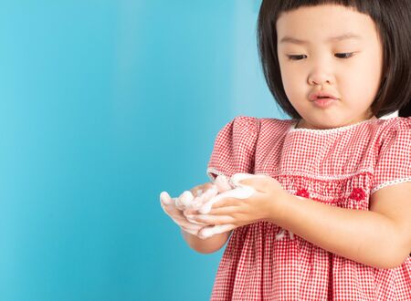 Cute Asian girl washing hands with soap bubbles to kill bacteria COVID - 19 for good health with fun and happiness. With copy space.の写真素材