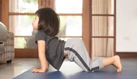 Asian girls and mothers are doing yoga by watching and following the example from online yoga tutorial videos are to use the free time to benefit during the holidays at home, during the time of the Covid-19 outbreak.の写真素材