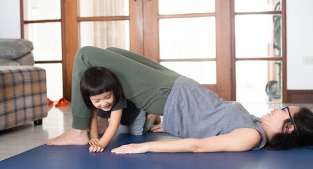Asian girls and mothers are doing yoga by watching and following the example from online yoga tutorial videos are to use the free time to benefit during the holidays at home, during the time of the Covid-19 outbreak.の写真素材
