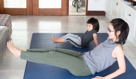Asian girls and mothers are doing yoga by watching and following the example from online yoga tutorial videos are to use the free time to benefit during the holidays at home, during the time of the Covid-19 outbreak.の写真素材
