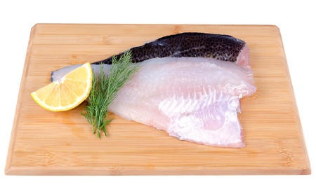 Raw cod fish fillets on wooden board 
