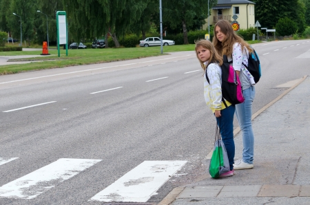 Girls look for the cars before street crossingの写真素材
