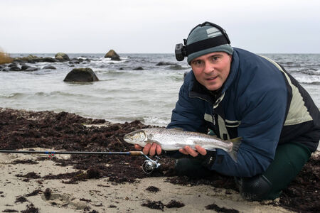 Portrait of angler with sea trout on the beach