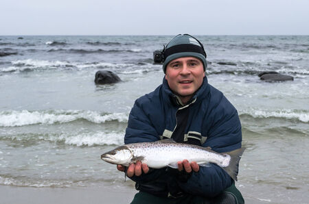 Happy angler with winter sea troutの写真素材