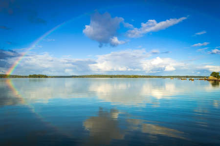 September rainbow over Swedish lakeの写真素材