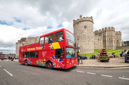 WINDSOR, UNITED KINGDOM - JULY 10, 2016: Red open topped Windsor tour bus in front of Windsor castle, Berksire, England, Western Europe, July 10, 2016.のeditorial素材