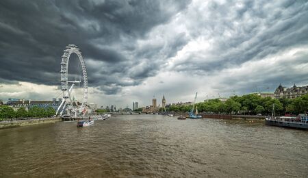 LONDON, UK - 16 JULY, 2016: London panoramic view from Hungerford bridge with famous landmarks, Big Ben, Houses of Parliament, London Eye and ships on River Thames with stormy sky - England, UKのeditorial素材