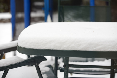 Heavy snowfall on a garden table and chairsの写真素材