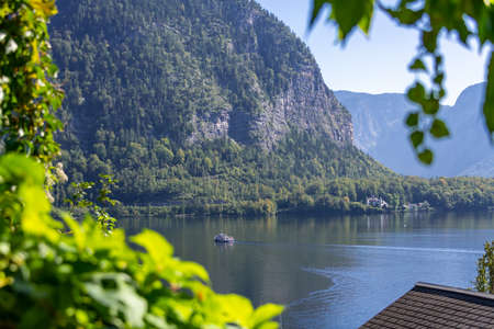 Ferry on Lake Hallstatt leaving the village on a sunny morningの写真素材