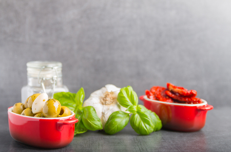 olives and dried tomatoes and spices on a stone backgroundの写真素材