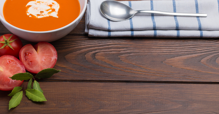 top view of fresh tomato soup on a wooden table with a spoonの写真素材