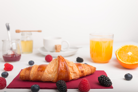 Homemade croissants on a breakfast table with fresh fruit juice and coffee and fresh fruit.の写真素材