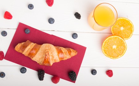 Homemade croissants on a breakfast table with fresh fruit juice and coffee and fresh fruit.の写真素材