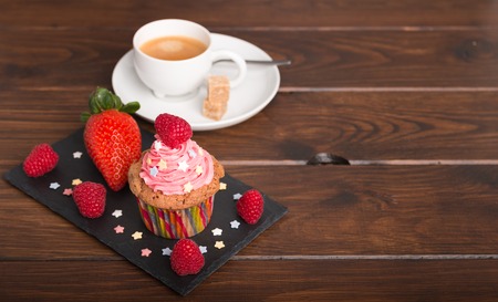 home baked cupcakes with colorful frosting and fruit with coffeeの写真素材