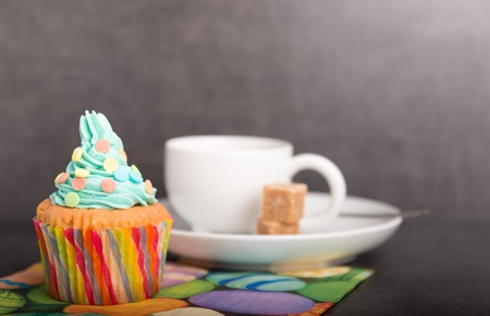 home baked cupcakes with colorful frosting and fruit with coffee and a easter napkinの写真素材