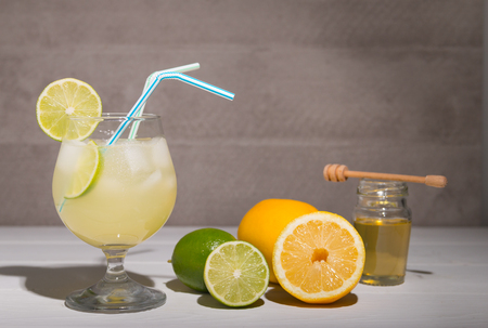 freshly made lemonade on a stone table with lemons and limes and honeyの写真素材