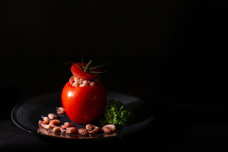 tomato with shrimps on a dark plate.の写真素材