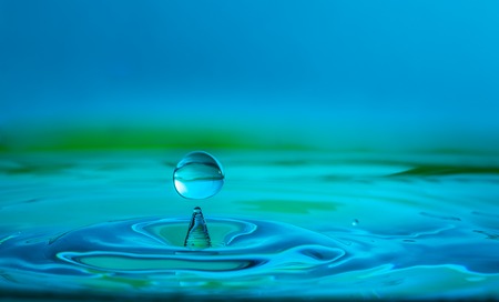 water drop splashing on a body of water in transparent blue.