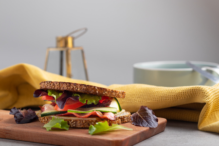 Homemade toast with bacon,cheese tomatoes and salad on a wooden cutting boardの写真素材